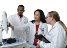 Two women and a man in labcoats looking at a screen on a medical device