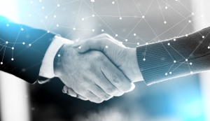 Two people in business attire shaking hands, symbolizing partnership and collaboration, with a digital network overlay.